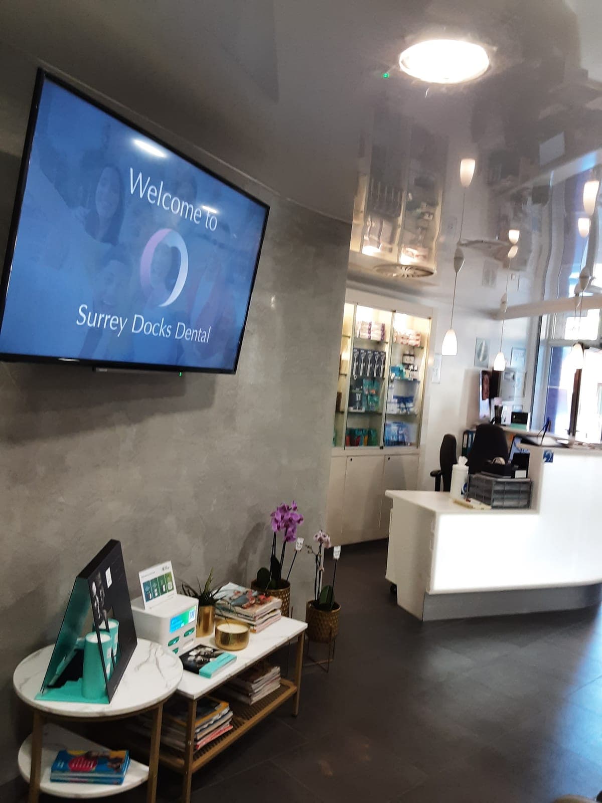 The reception at Surrey Docks Dental, with a Welcome to Surrey Docks Dental screen on the wall
